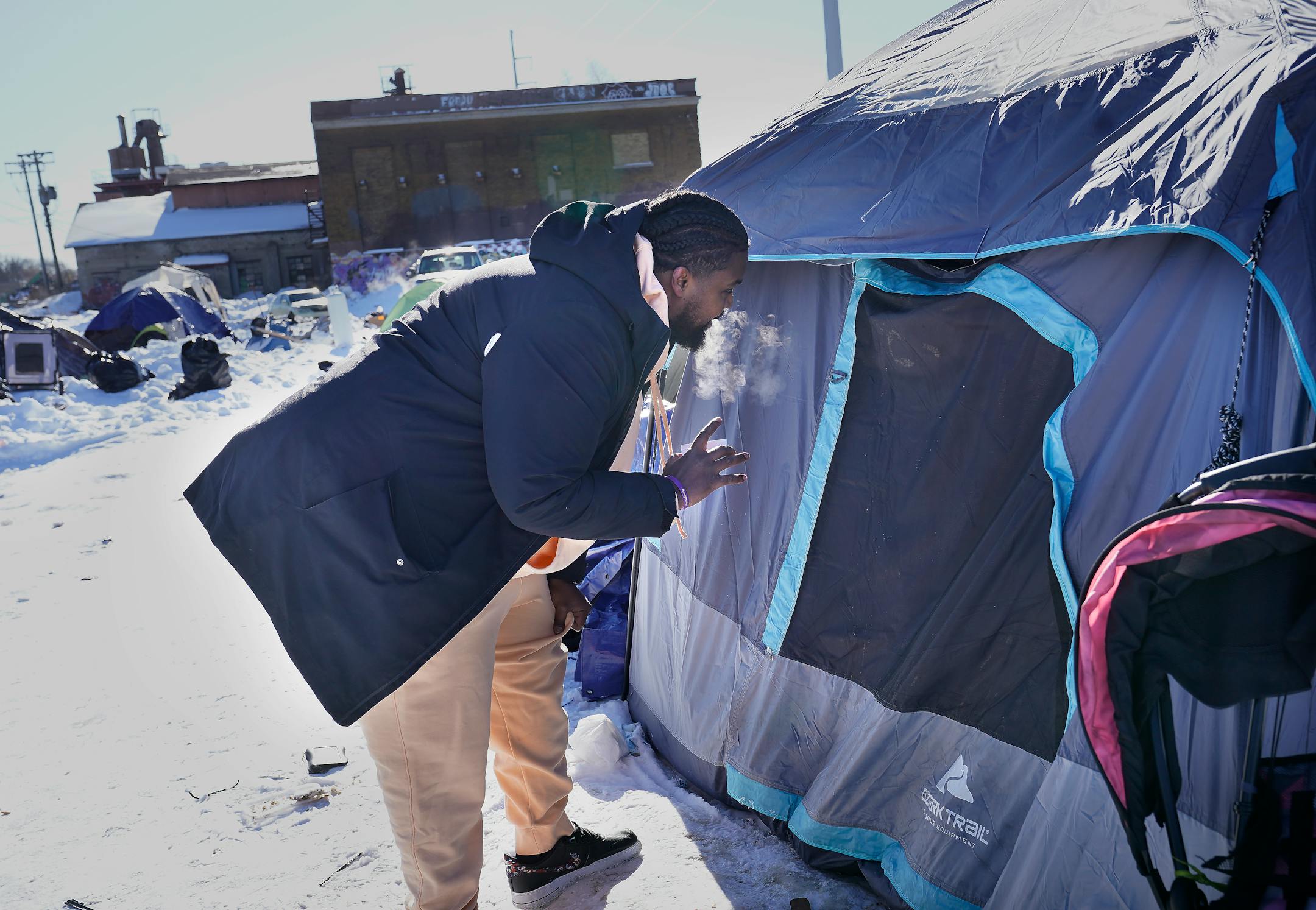 Muad A., a housing access coordinator for The Housing Guy, a social service organization serving Twin Cities adults needing housing and resources, talks to a resident of a homeless encampment in their tent, off of the 3000 block of Snelling Avenue, near Hiawatha Ave.
