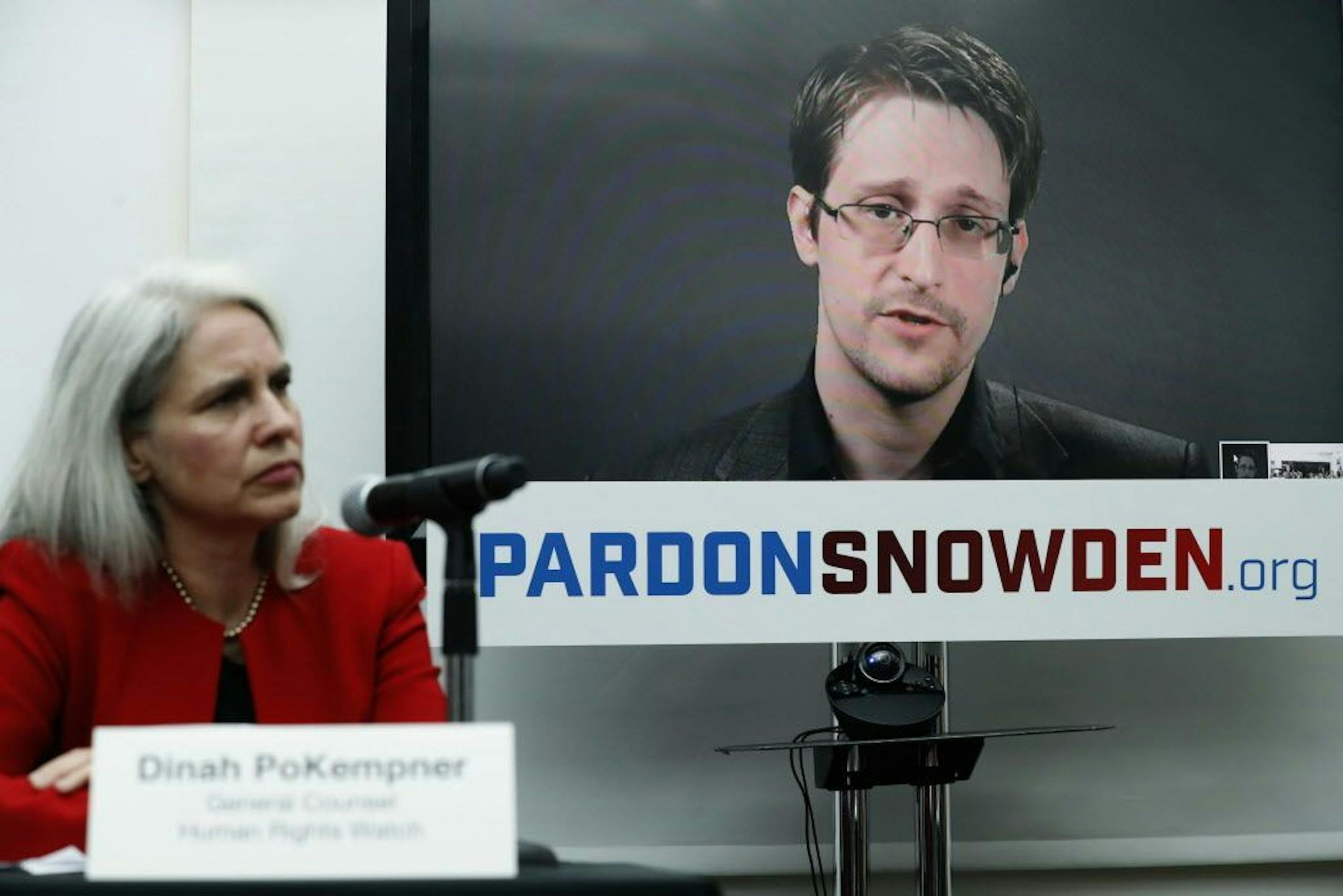 Dinah PoKempner, left, general council for Human Rights Watch, listens as Edward Snowden speaks on a television screen via video link from Moscow during a news conference to call upon President Barack Obama to pardon Snowden before he leaves office, Wednesday, Sept. 14, 2016, in New York. Human and civil rights organizations, including the ACLU, Human Rights Watch and Amnesty International, launched a public campaign to persuade Obama to pardon the former National Security Agency contractor, who