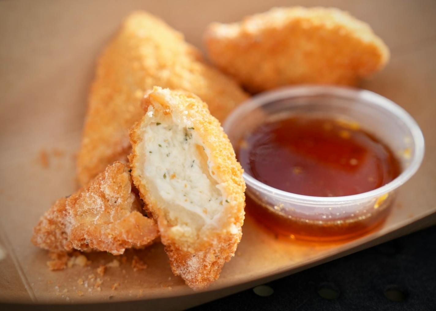 Three deep-fried ranch pieces and hot honey dipping sauce.