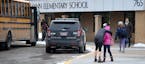 Meghan Stephenson hugs her child before staying goodbye outside Orono Schumann Elementary School as a police officer stands nearby as students arrive 