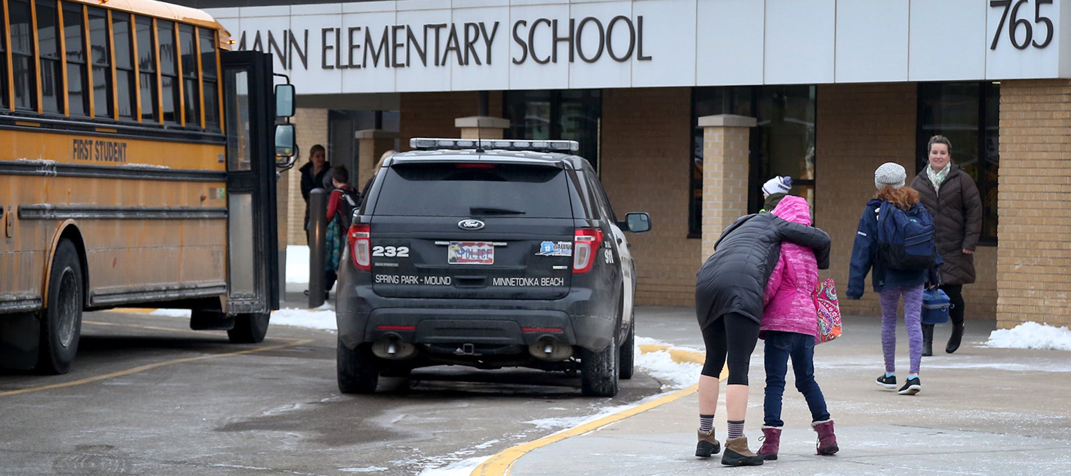 Meghan Stephenson hugs her child before staying goodbye outside Orono Schumann Elementary School as a police officer stands nearby as students arrive for the day Thursday, Feb. 22, 2018, a day after a threat was posted, causing Orono schools to go on lockdown. A student was arrested at the high school Wednesday after a threat of gun violence. Stephenson said she has children in all four of Orono's schools and she praised for how they dealt with the threat.] DAVID JOLES Ô david.joles@startri