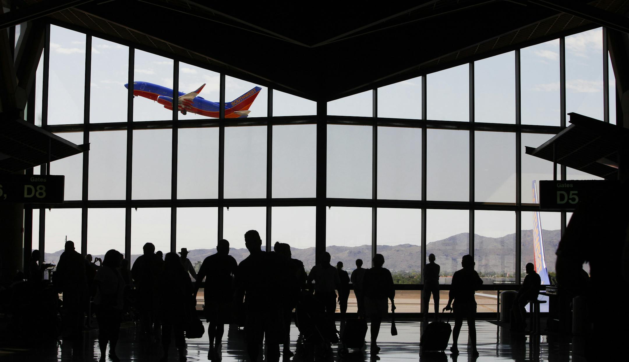 The silhouettes of travelers are seen as a Southwest Airlines Co. plane takes off from Phoenix Sky Harbor International Airport (PHX) in Phoenix, Arizona, U.S., on Friday, Sept. 6, 2013. Yields on benchmark securities climbed to almost two-year highs as consumers spent more on travel and tourism while manufacturing expanded &#xec;modestly&#xee; from early July through late August, according to the Federal Reserve&#xed;s Beige Book. Photographer: Patrick T. Fallon/Bloomberg ORG XMIT: 180274718