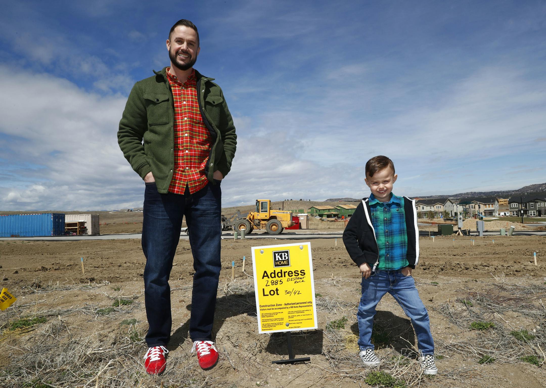 In this Saturday, April 7, 2018, photo, Chad Zolman, left, joins his 5-year-old son, Quinten, in standing at the site of their yet-to-be-constructed new home in Castle Rock, Colo. A tight housing market, further complicated by climbing interest rates and rising prices, has forced buyers such as Zolman to move farther out of the Denver metropolitan area. Zolman eventually bought a newly built, three-bedroom townhome for $370,000. (AP Photo/David Zalubowski)