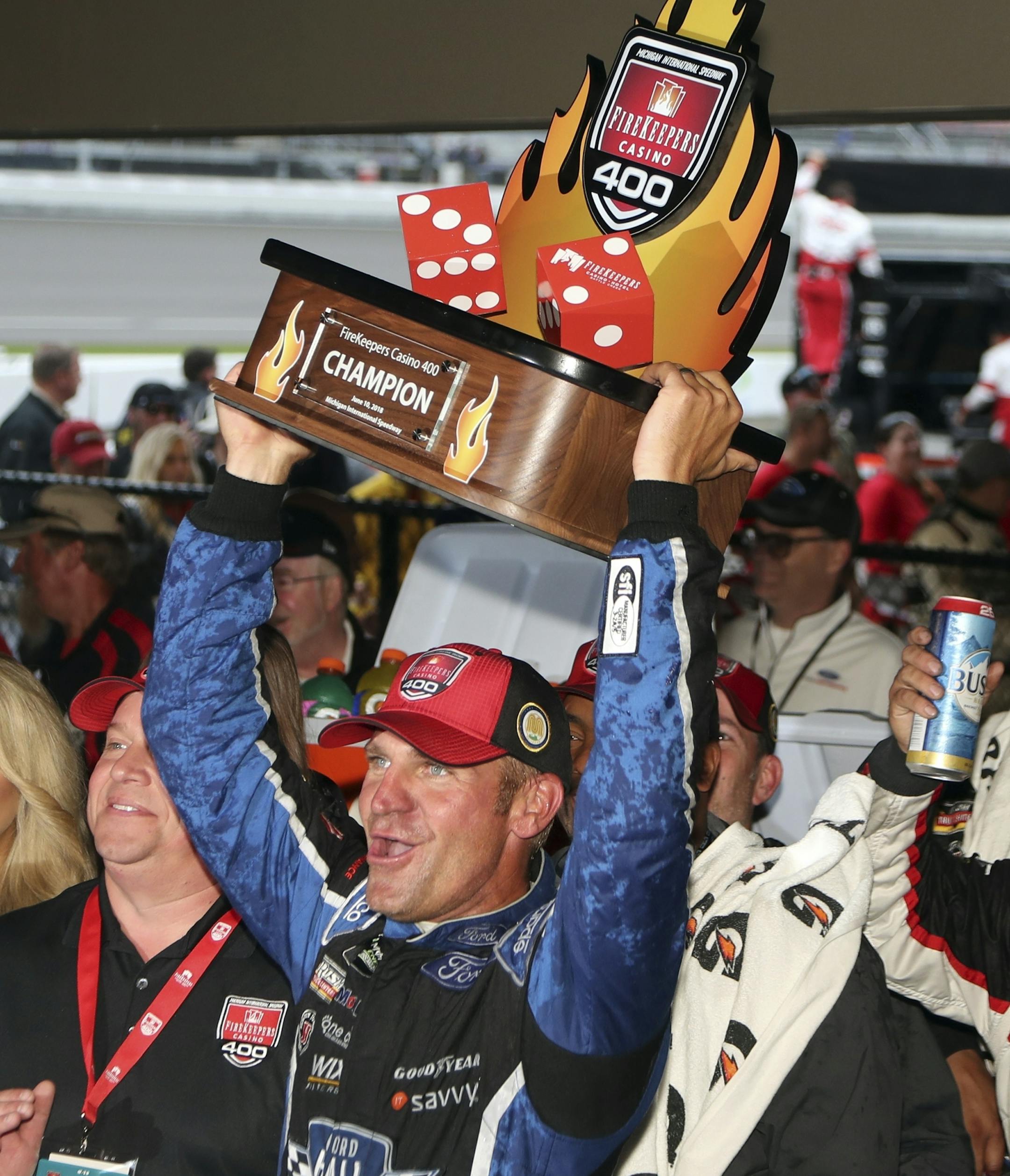 Clint Bowyer holds the Firekeepers Casino 400 trophy after winning a shortened NASCAR Cup Series auto race, Sunday, June 10, 2018, in Brooklyn, Mich. (AP Photo/Carlos Osorio)