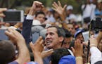 Venezuela's opposition leader and self-proclaimed interim president Juan Guaid&#xf3; holds up his right fist symbolizing solidarity during a rally in 