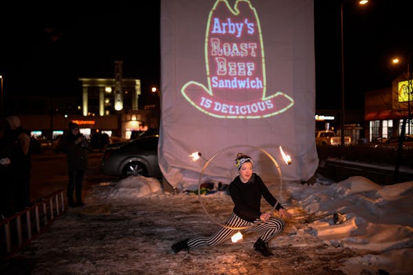 Chloe Bosak , of Andover, fire danced in front of a projected Arby's logo that was put in place of the recently-removed sign.