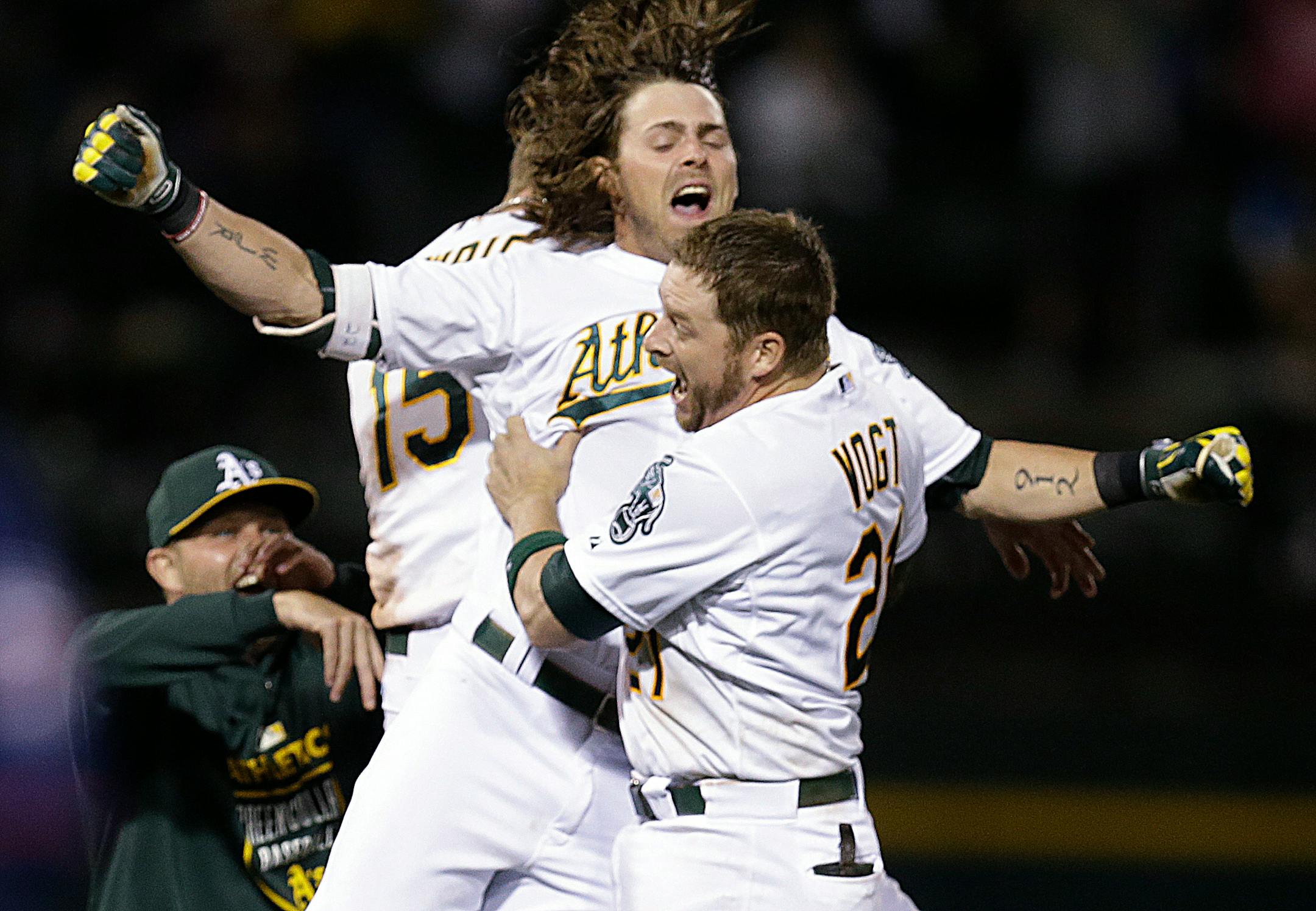 Oakland Athletics' Stephen Vogt (21) and Josh Reddick celebrate after Vogt drove in the winning run against the Minnesota Twins in the 10th inning of a baseball game Saturday, July 18, 2015, in Oakland, Calif. (AP Photo/Ben Margot)