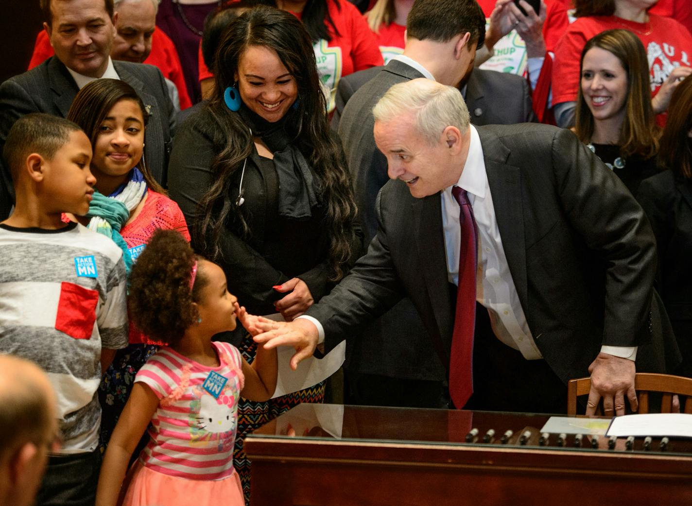 Governor Mark Dayton high-fived Ashia Rhodes. She was there with her sister Jada, brother Mario and mother Jacquita Berens who works three jobs and will benefit from the minimum wage increase. Governor Dayton signed the minimum wage bill into law at a public bill signing ceremony Monday the Minnesota State Capitol Rotunda. The bill, which was passed by the Legislature last week, will increase Minnesota&#x2019;s minimum wage to $9.50 per hour, and index it to inflation. ] GLEN STUBBE * gstubbe@st