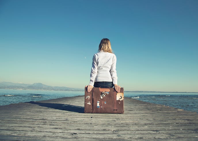 woman sitting on her suitcase waiting for the sunset in a spectacular view