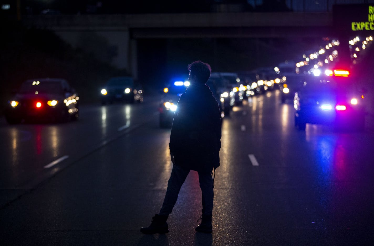 A protestor stood in front of police cars as a human barrier between the police cars and the larger group of people. The protestors shut down I-494 W for about half an hour on Sunday afternoon to protest police shootings and honor Brian Quinones who was shot and killed by police in Richfield on Saturday night.