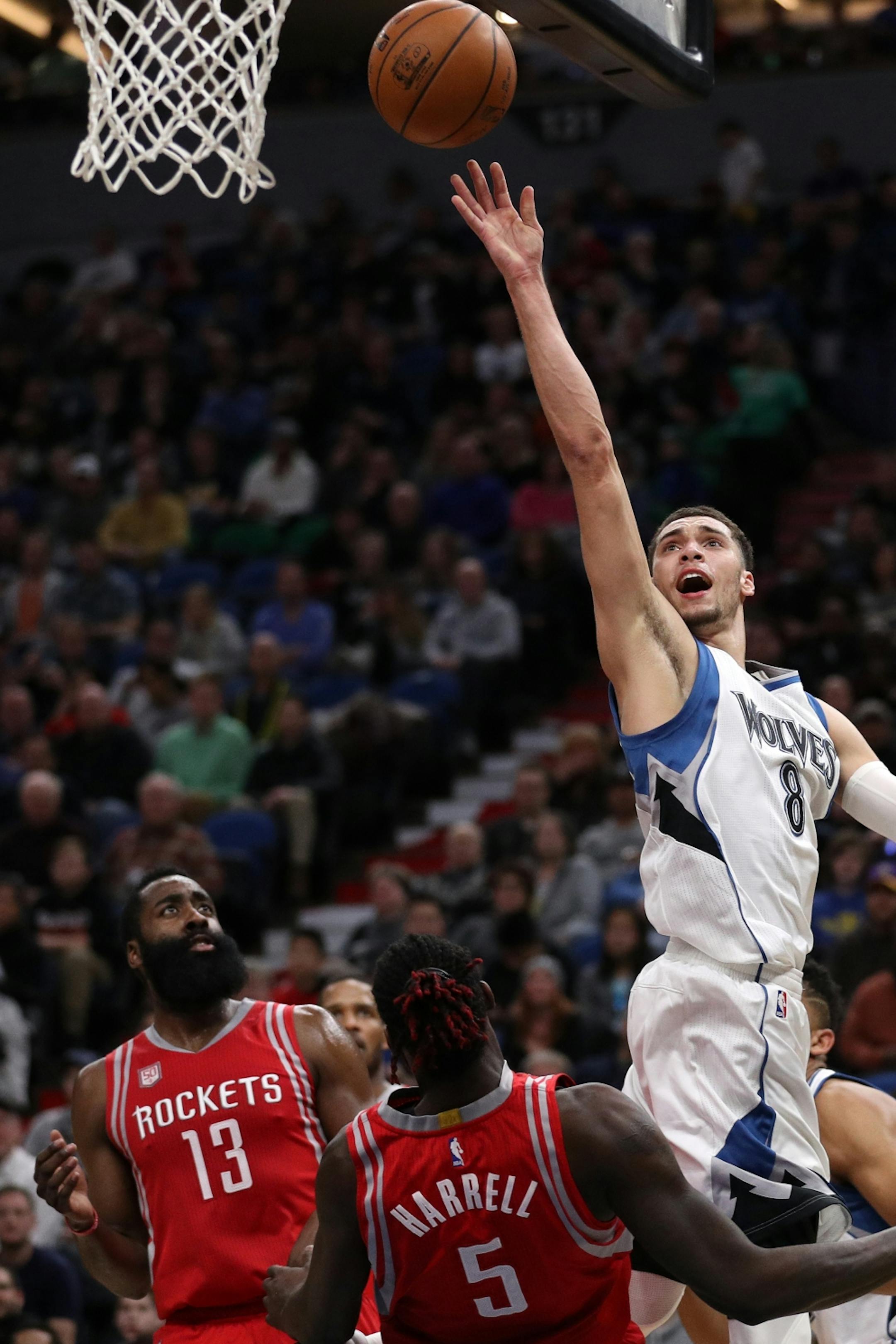 Minnesota Timberwolves guard Zach LaVine (8) makes a layup over Houston Rockets forward Montrezl Harrell (5) and Houston Rockets guard James Harden (13) in the first half.