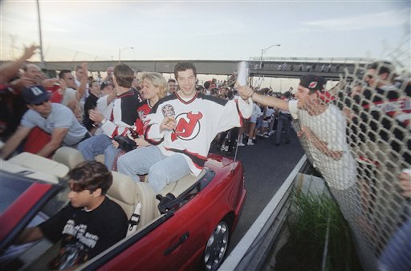 A New Jersey Devils fan reaches out past a security fence to touch Devils' Bill Guerin during a celebratory motorcade around the Meadowlands Arena for the Stanley Cup Champions, Wednesday, June 28, 1995 in East Rutherford, N.J. (AP Photo/Julio Ibarra)