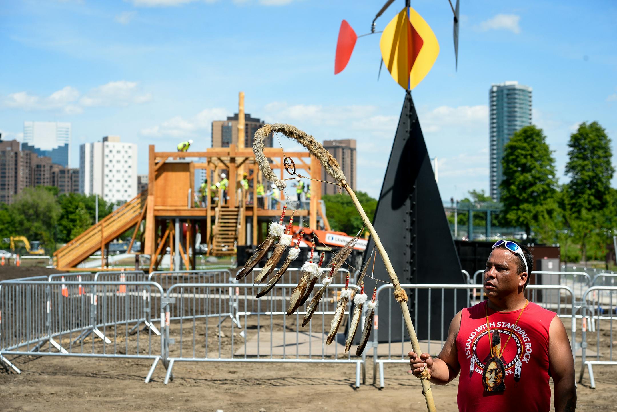 Tommy Tiokasin, with the Standing Rock Sioux Nation, held a staff from his tribal community as the "Scaffold" sculpture was dismantled behind him. Tiokasin says he is related to two of the men hung in the Dakota 38 hangings. ] AARON LAVINSKY • aaron.lavinsky@startribune.com Demolishment of the "Scaffold" sculpture began Friday, June 2, 2017 at the Minneapolis, Sculpture Garden in Minneapolis, Minn.