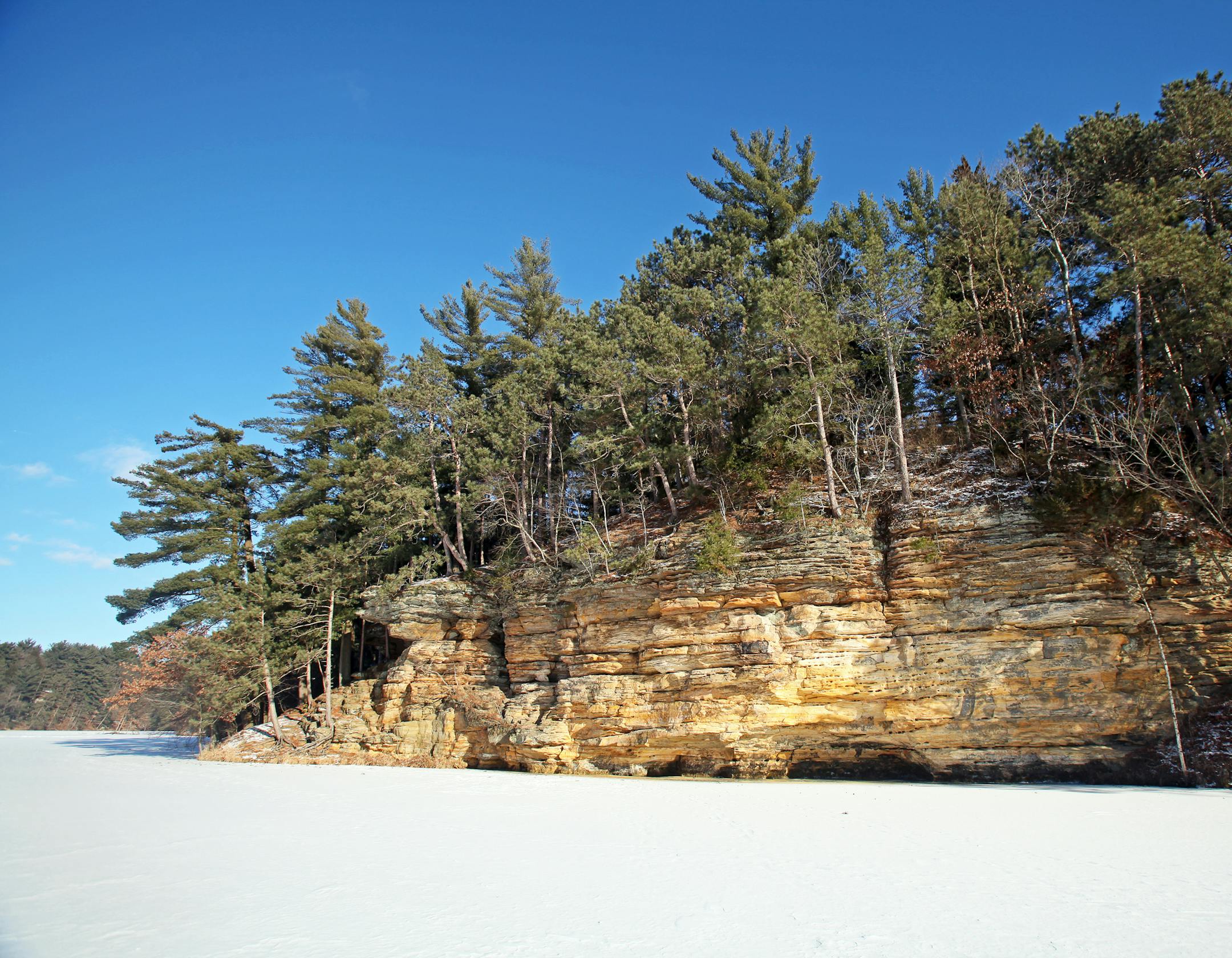 The sandstone cliffs at Mirror Lake State Park provide a stunning contrast with the white snow on the frozen lake.