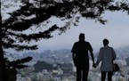 FILE- In this July 3, 2017, file photo a man and woman walk under trees down a path at Alta Plaza Park in San Francisco. Looking at the income, living