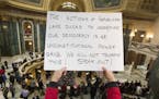 People protest the legislature's extraordinary session during the official Christmas tree lighting ceremony at the Capitol in Madison, Wis., Tuesday, 