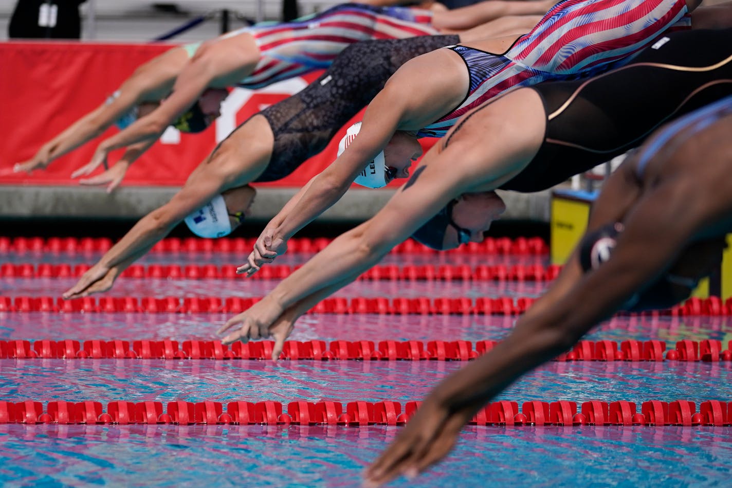 Katie Ledecky, center, and other swimmers jump in the pool at the start of the women's 100-meter freestyle final at the TYR Pro Swim Series swim meet Sunday, April 11, 2021, in Mission Viejo, Calif. (AP Photo/Ashley Landis)