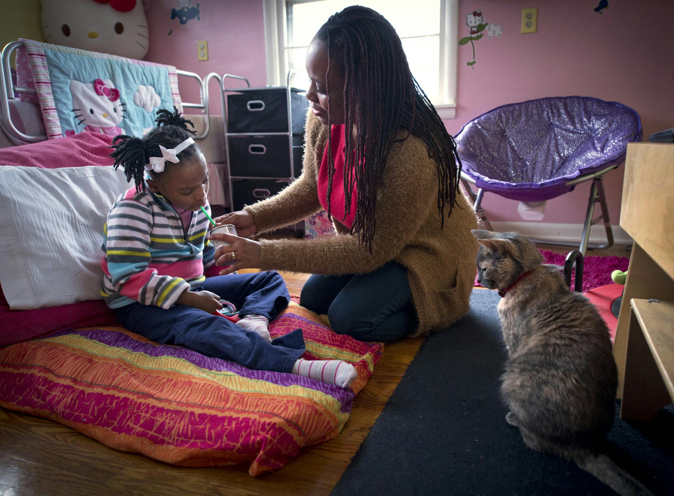 Millie McWilliams, left, 9, is given a nutrition drink by her mother, Angela McWilliams, at their home on Wednesday, Dec. 3, in Kansas City, Mo. A new genetic test by Children's Mercy Hospital researchers has made it possible to diagnose a developmental disorder that affects Millie. (Keith Myers/Kansas City Star/TNS)