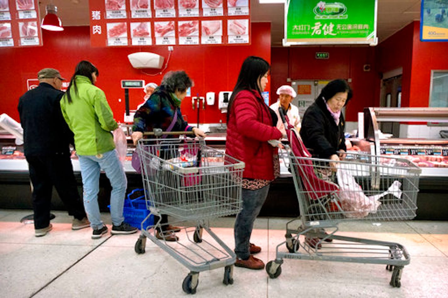 Customers shop for pork at a supermarket in Beijing, Friday, March 23, 2018. China announced a $3 billion list of U.S. goods including pork, apples and steel pipe on Friday that it said may be hit with higher tariffs in a spiraling trade dispute with President Donald Trump that companies and investors worry could depress global commerce. (AP Photo/Mark Schiefelbein)