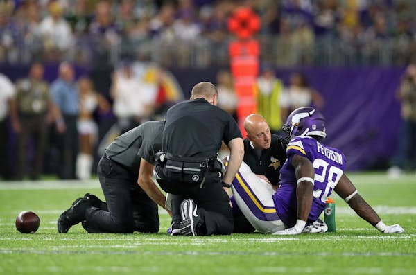 Adrian Peterson is tended to by the training staff after his knee injury in the third quarter of Sunday's game.