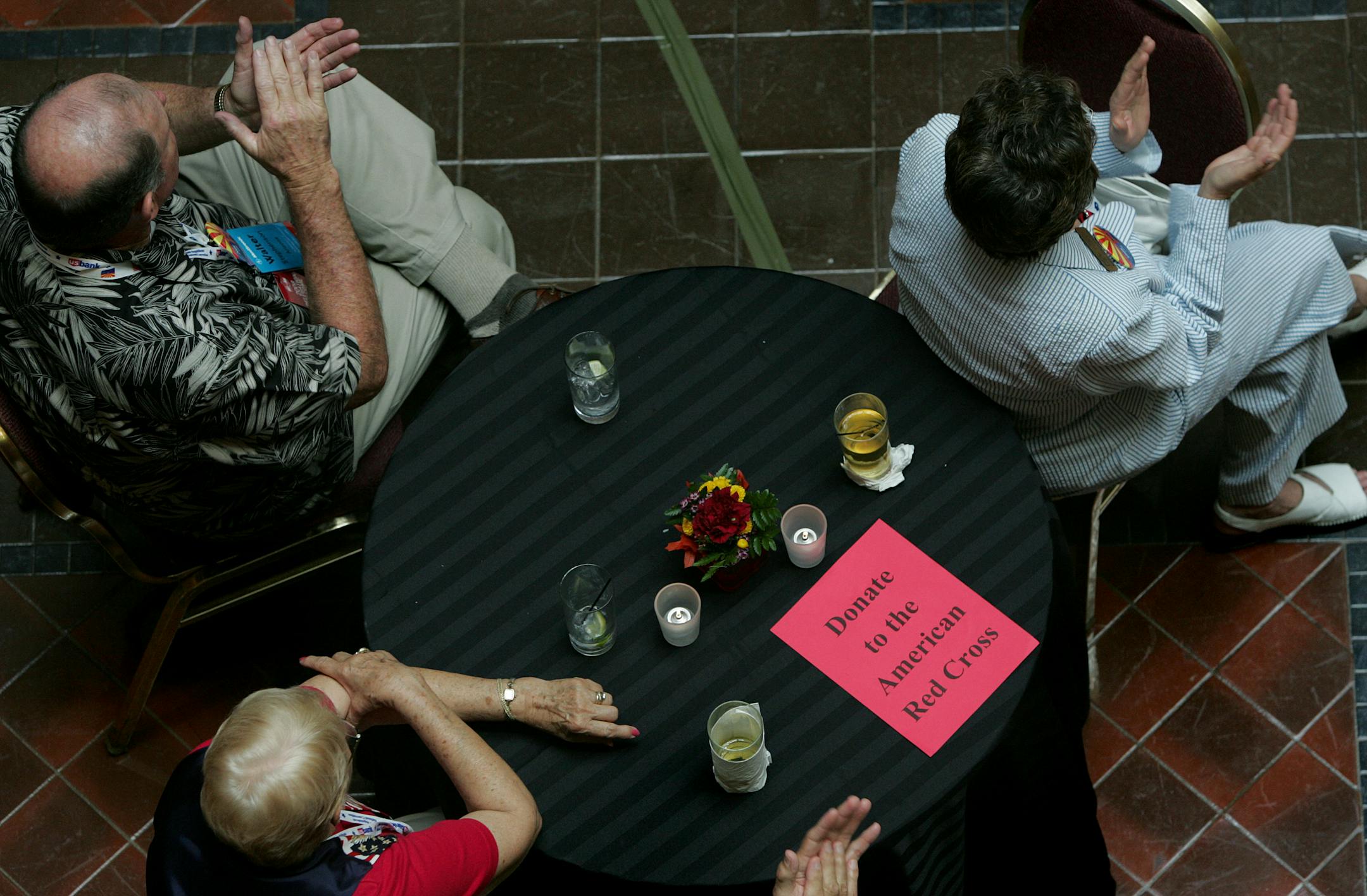 Arizona GOP convention delegates Walt and Anne Stephenson, upper left and right, and Gisela Kraus, lower left, with her husband Horst Kraus, not pictured, clapped for a speaker at a party for the Arizona and Minnesota delegations at the Landmark Center. On each table was a red note reminding delegates they could make a contribution to Hurricane Gustav relief efforts through the American Red Cross.