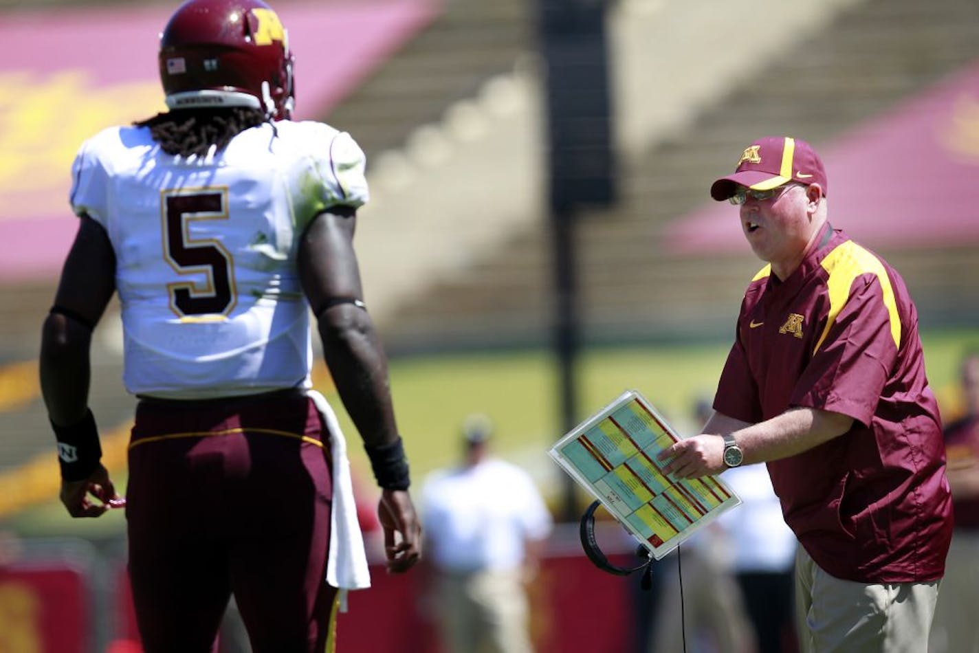 Minnesota quarterback MarQueis Gray (5) spoke with head coach Jerry Kill during a timeout in the second quarter.