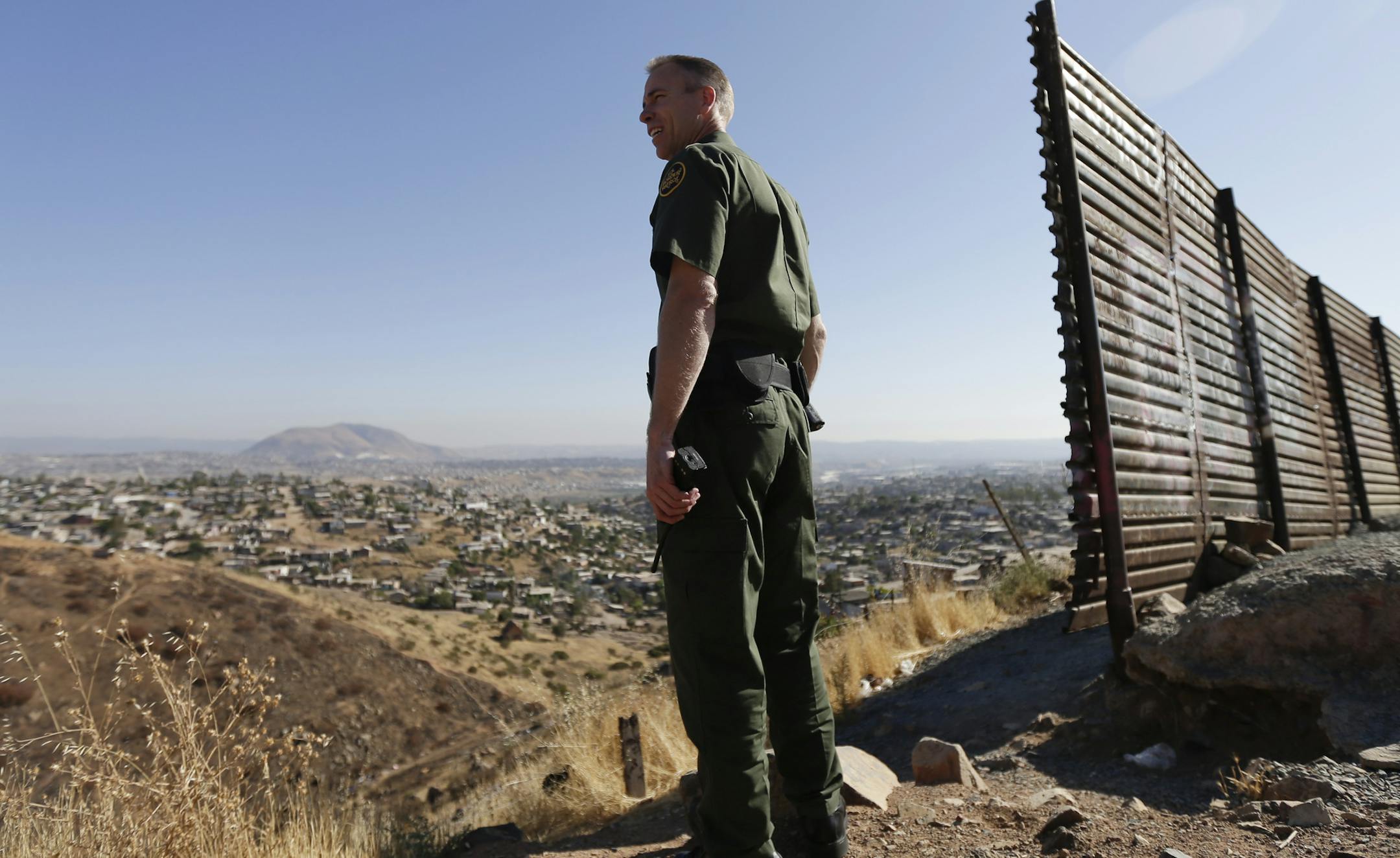 FILE - In this June 13, 2013 file photo, US Border Patrol agent Jerry Conlin looks out over Tijuana, Mexico, behind, along the old border wall along the US - Mexico border, where it ends at the base of a hill in San Diego.