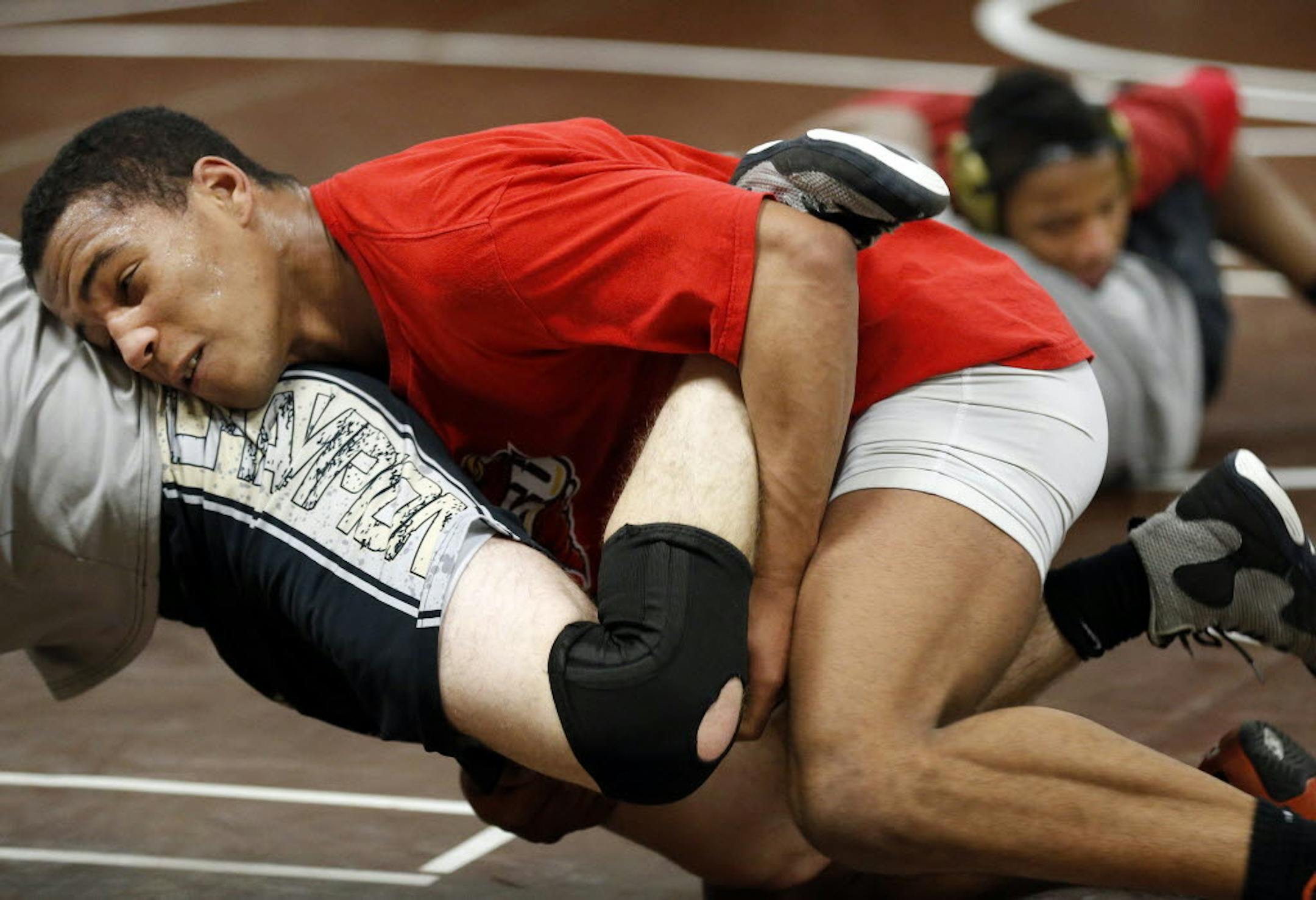 Apple Valley High School wrestlers Danny Woiwor (foreground in red) and his brother Maolu (background in red) practiced Monday. Danny, wrestling several classes above his normal weight, finished sixth at state at 182 pounds last year, while Maolu won the 106-pound crown. Photo by CARLOS GONZALEZ • cgonzalez@startribune.com