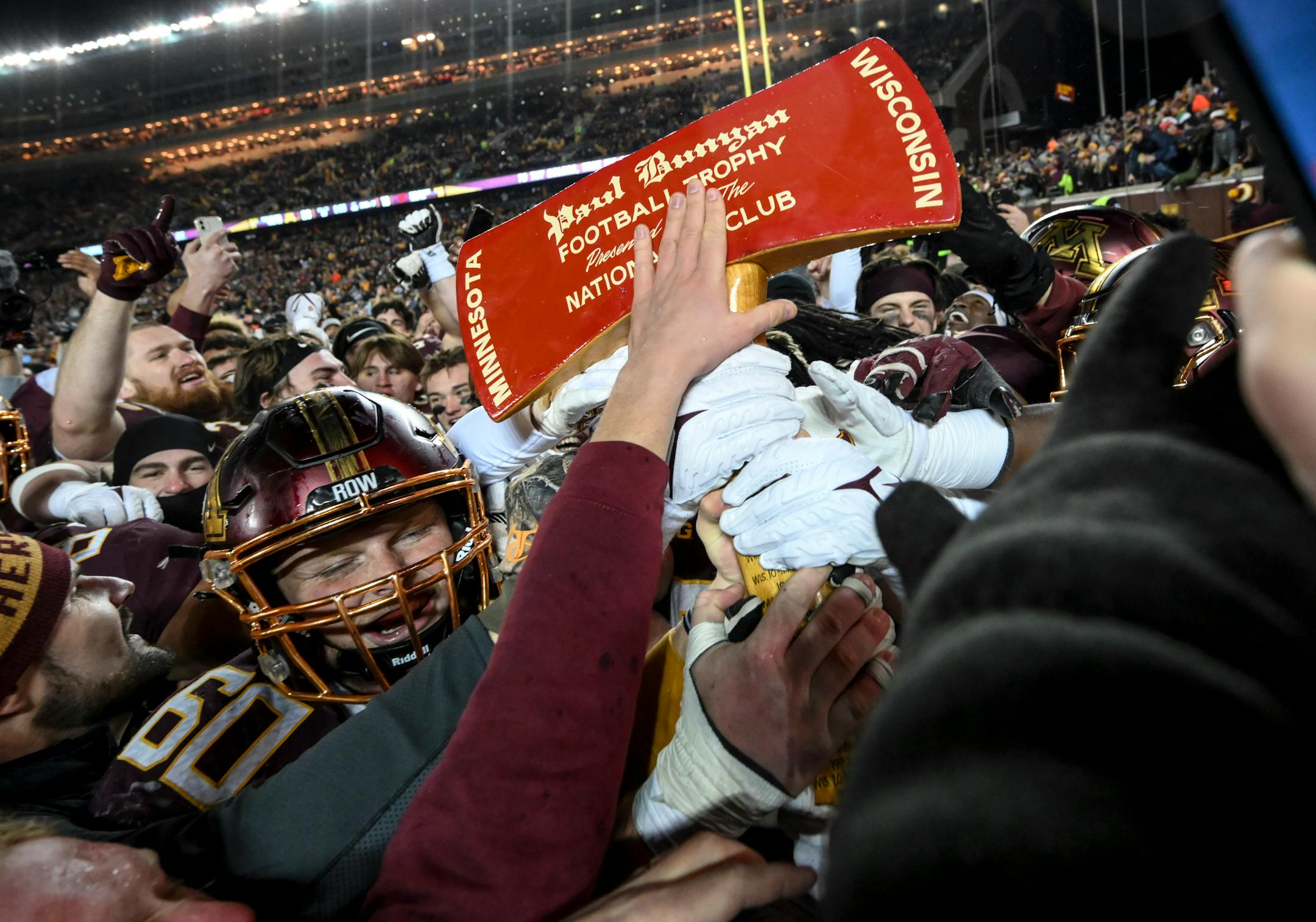 Minnesota Gophers players, including offensive lineman John Michael Schmitz (60), celebrate with Paul Bunyan's Axe after an NCAA football game between the Gophers and the Wisconsin Badgers Saturday, Nov. 27, 2021 at Huntington Bank Stadium in Minneapolis, Minn. Minnesota defeated Wisconsin 23-13. ] AARON LAVINSKY • aaron.lavinsky@startribune.com