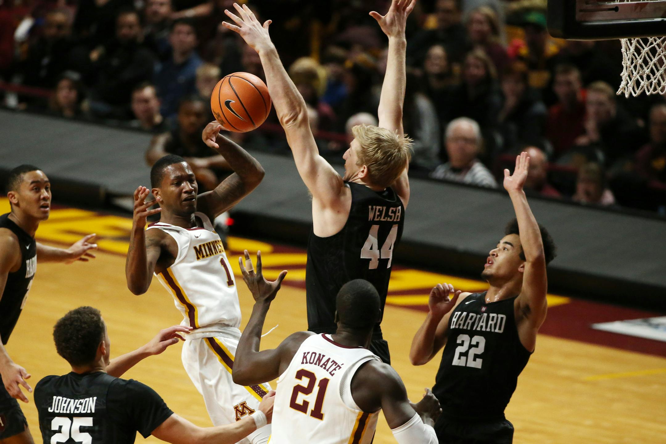 Gophers guard Dupree McBrayer passed the ball to center Bakary Konate around Crimson forward Henry Welsh on Saturday