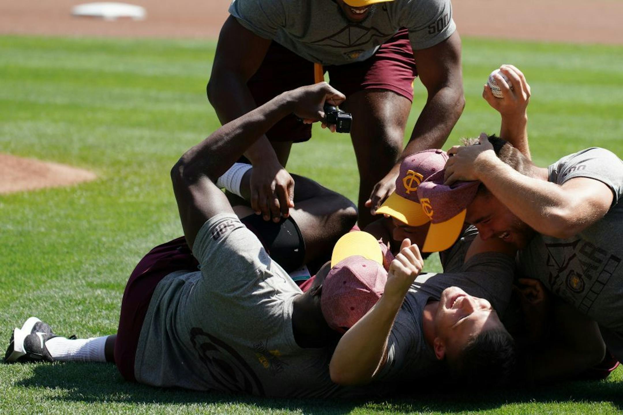 Gophers wide receiver Clay Geary (18) was mobbed by his teammates as he found out he is a scholarship recipient after throwing out a ceremonial first pitch ahead of Wednesday's Twins game.