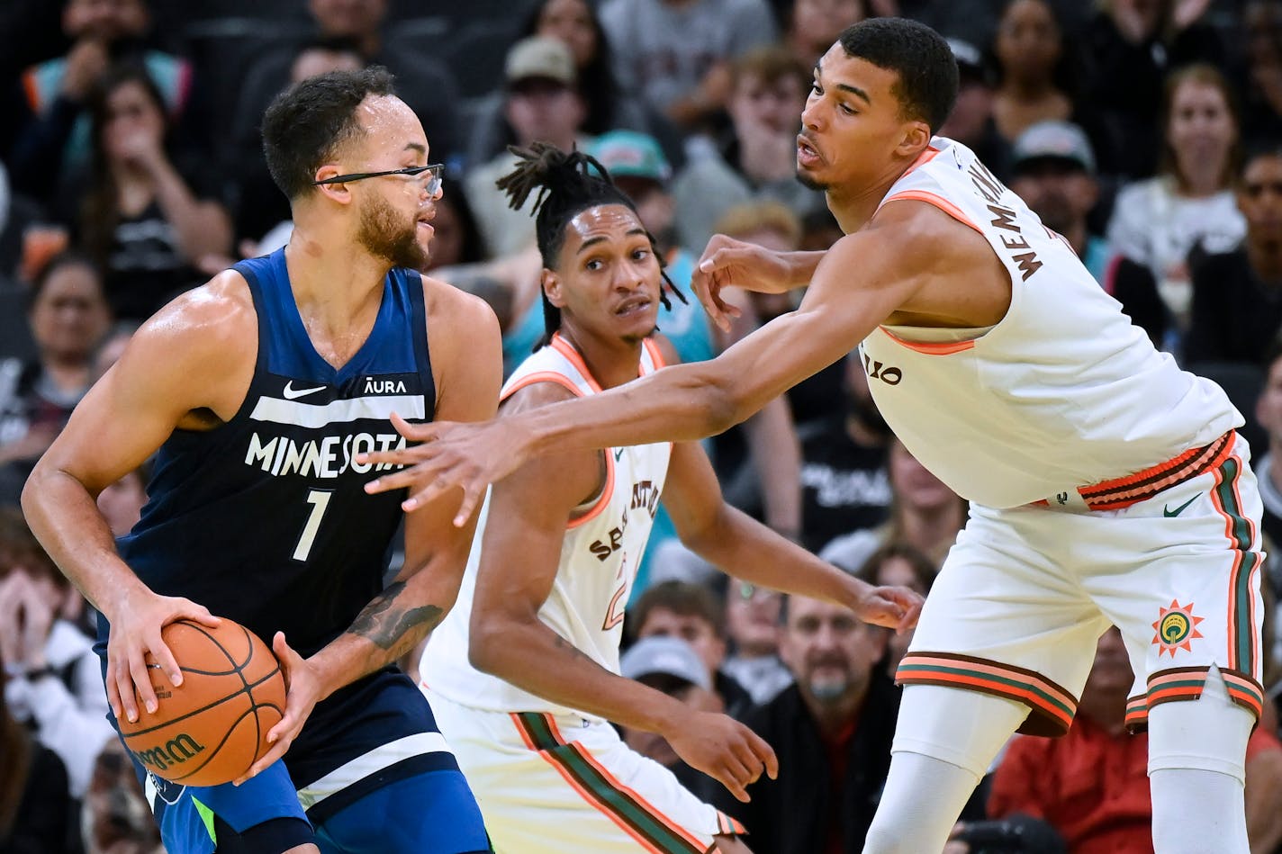 Minnesota Timberwolves' Kyle Anderson, left, is defended by San Antonio Spurs' Victor Wembanyama, right, and Devin Vassell during the second half of an NBA basketball in-season tournament game Friday, Nov. 10, 2023, in San Antonio. (AP Photo/Darren Abate)