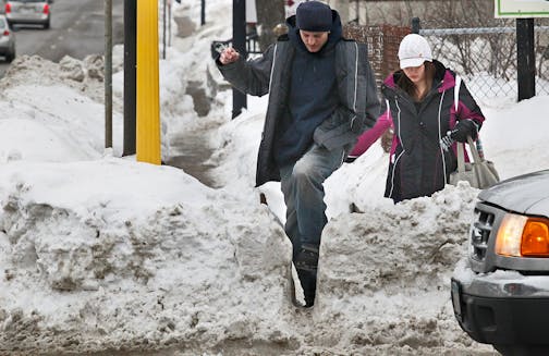 Pedestrians fight their way through a narrow opening at a crosswalk in Minneapolis.