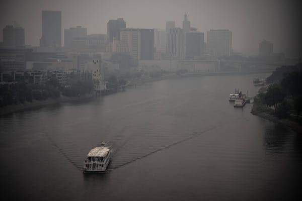 A boat goes north on the Mississippi River as heavy smoke from wildfire blankets downtown St. Paul last June.