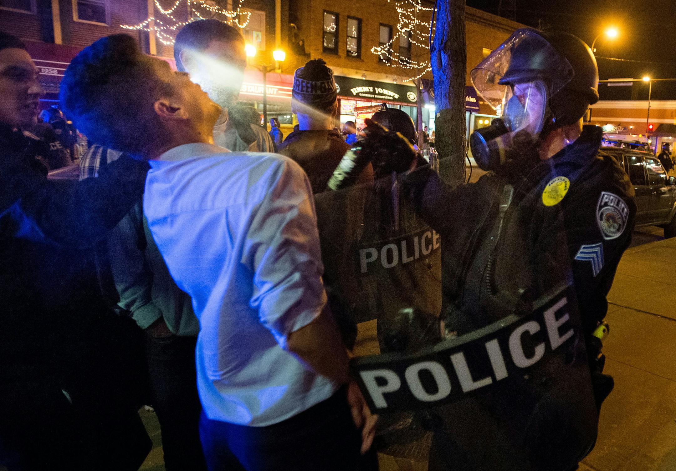 A Minneapolis police officer sprays a person during a raucous celebration by University of Minnesota hockey fans that resulted in several arrests Thursday night, April 10, 2014 in Minneapolis. Hundreds of students and other hockey fans took to the streets in Dinkytown near campus to celebrate the Gophers' last-second Frozen Four semifinal win over North Dakota. (AP Photo/The Minnesota Daily, Bridget Bennett) ORG XMIT: MIN2014041114465365