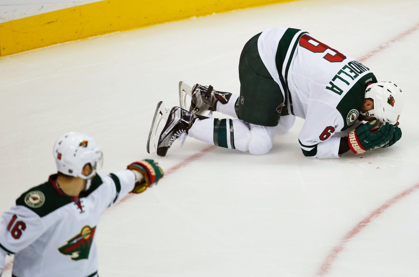 Wild defenseman Marco Scandella, right, spun to a stop after getting hit in the face while pursuing the puck against the Colorado Avalanche in the third period Monday. Wild left winger Jason Zucker, front, called for a stop in play after the injury. Colorado won 2-1 in overtime.