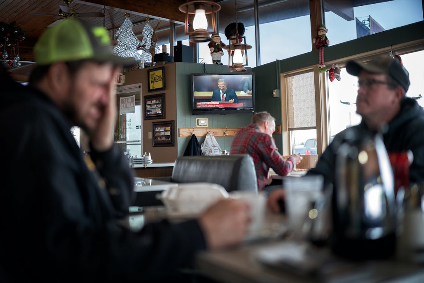 Cory Peine of Cannon Falls and Jay Anderson of Hastings occasionally glanced up at the impeachment hearings on television in the background at Little Oscar's Restaurant in Hampton on Wednesday.