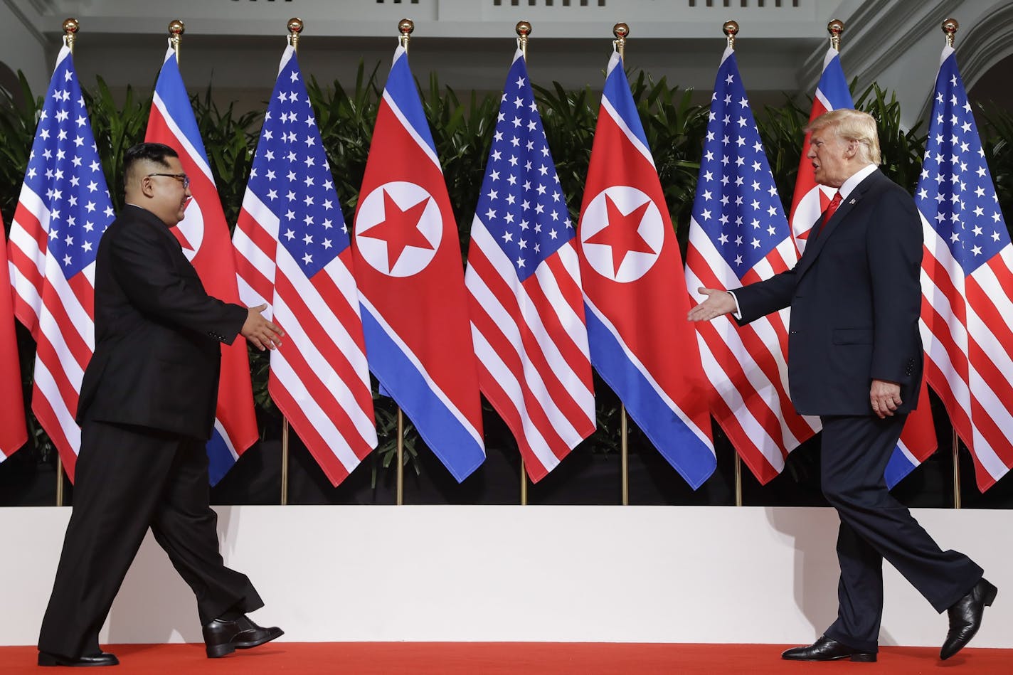 U. S. President Donald Trump and North Korea leader Kim Jong Un walks toward each other at the Capella resort on Sentosa Island Tuesday, June 12, 2018 in Singapore.