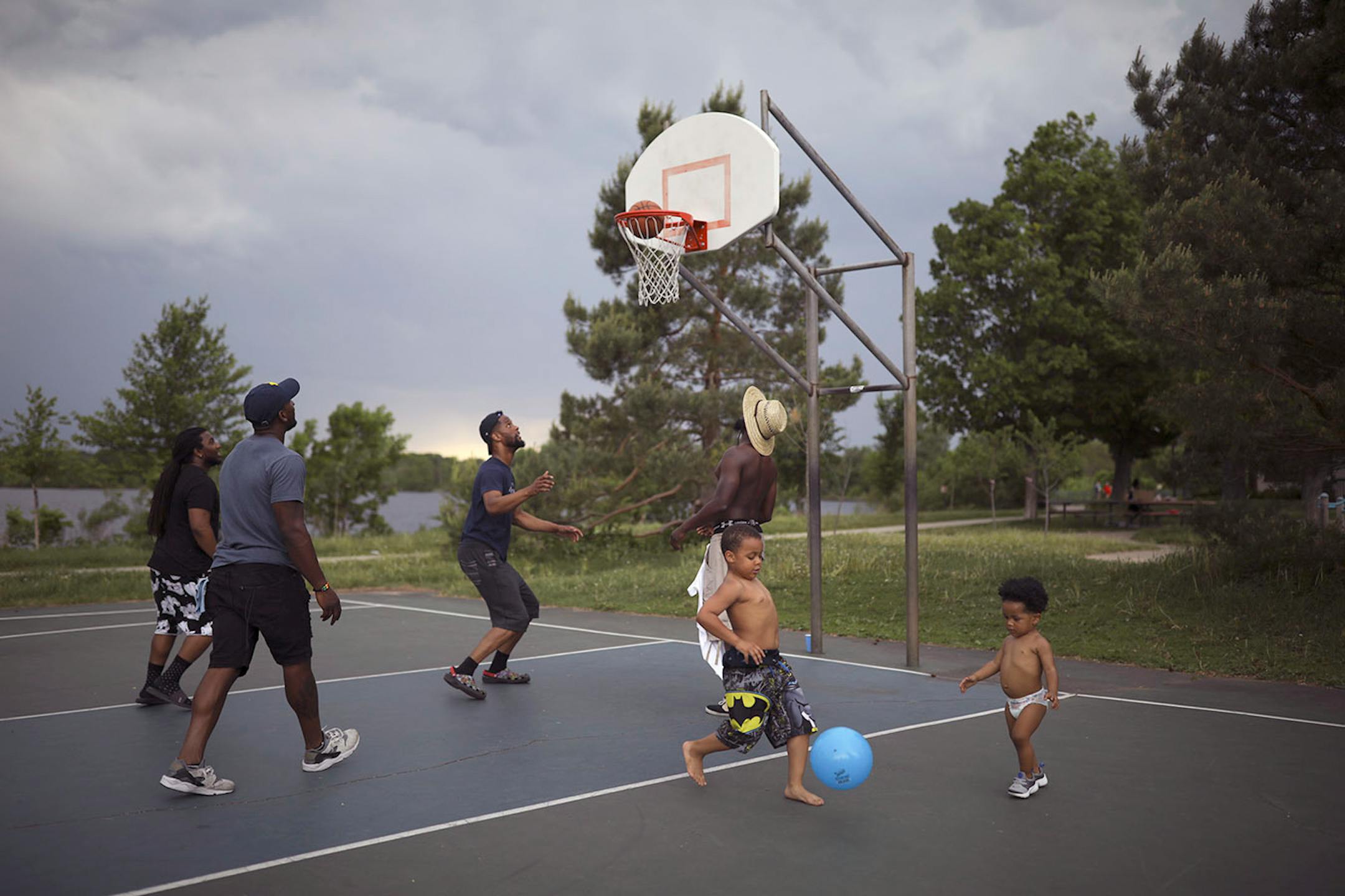 With rain threatening, friends, Jarret Westbrook, Warren Matthews, Mike Rose, and Tristan Smith played basketball while Jovon Robinson and Justice Rose, 1.5, right, played a game of their own near the grownups.