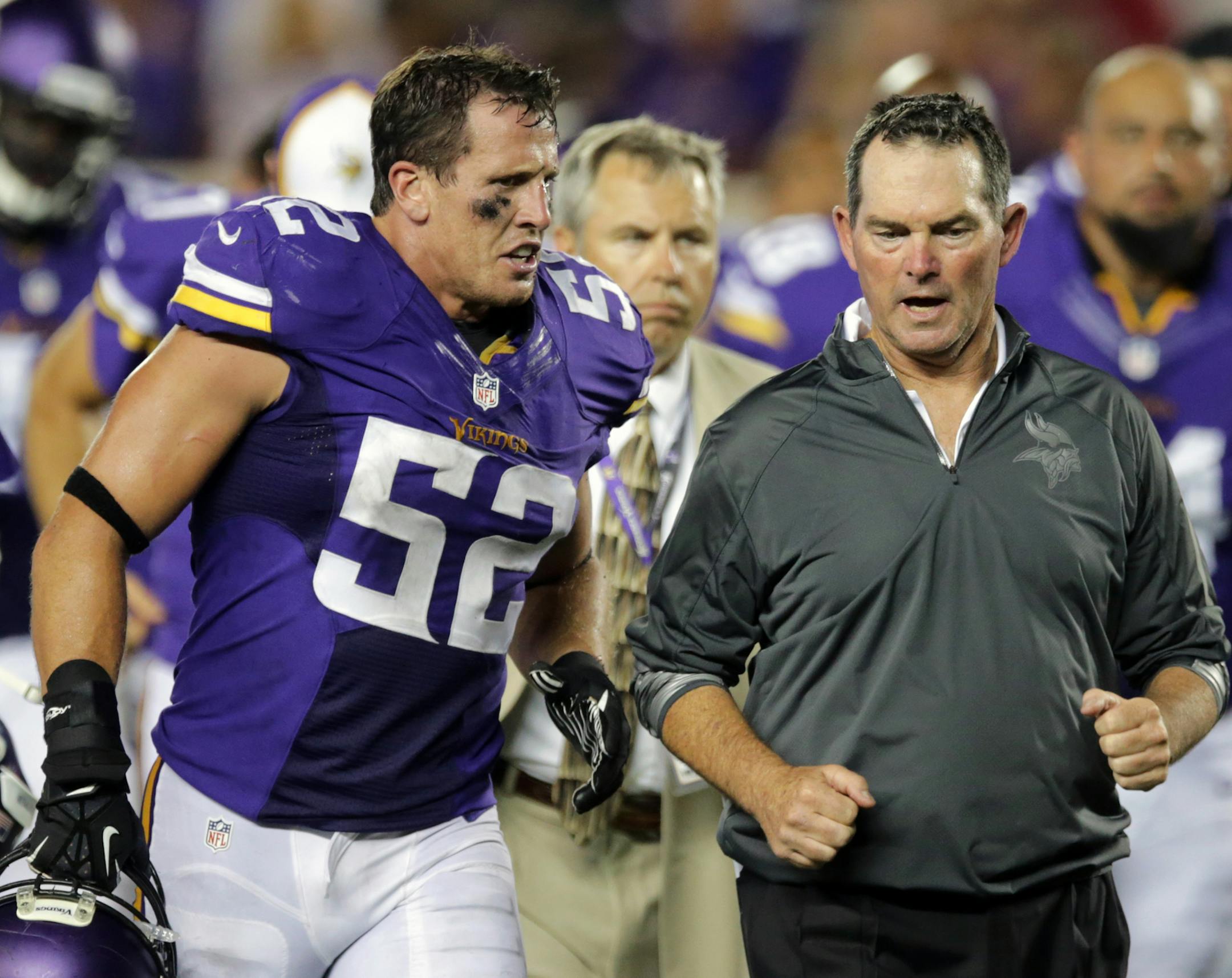 Minnesota Vikings outside linebacker Chad Greenway, left, runs off the field with head coach Mike Zimmer at the end of the first half of an NFL preseason football game against the Arizona Cardinals, Saturday, Aug. 16, 2014, in Minneapolis. (AP Photo/Jim Mone) ORG XMIT: MIN2014091113432555