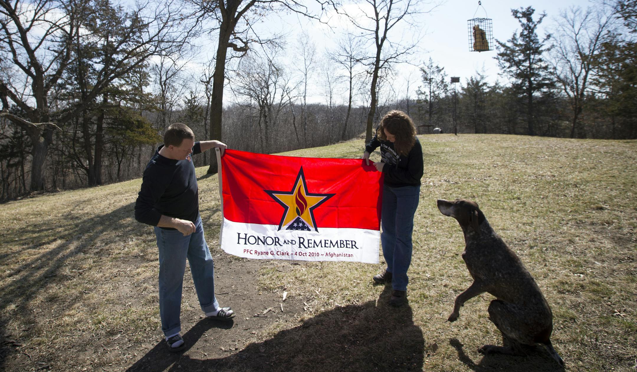 Rick and Tracy Clark held up the personalized Honor and Remember Flag they were given after their son Ryane Clark was killed while serving in Afghanistan. They were photographed at their home in New London, Minn., on Friday, April 10, 2015. At right is Ryane's dog Ozzie. ] RENEE JONES SCHNEIDER • reneejones@startribune.com Ryane CQ