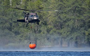 Crews from the Minnesota Army National Guard use Blackhawk helicopters to scoop water from Indian Lake as they worked to douse the Camp House fire nea