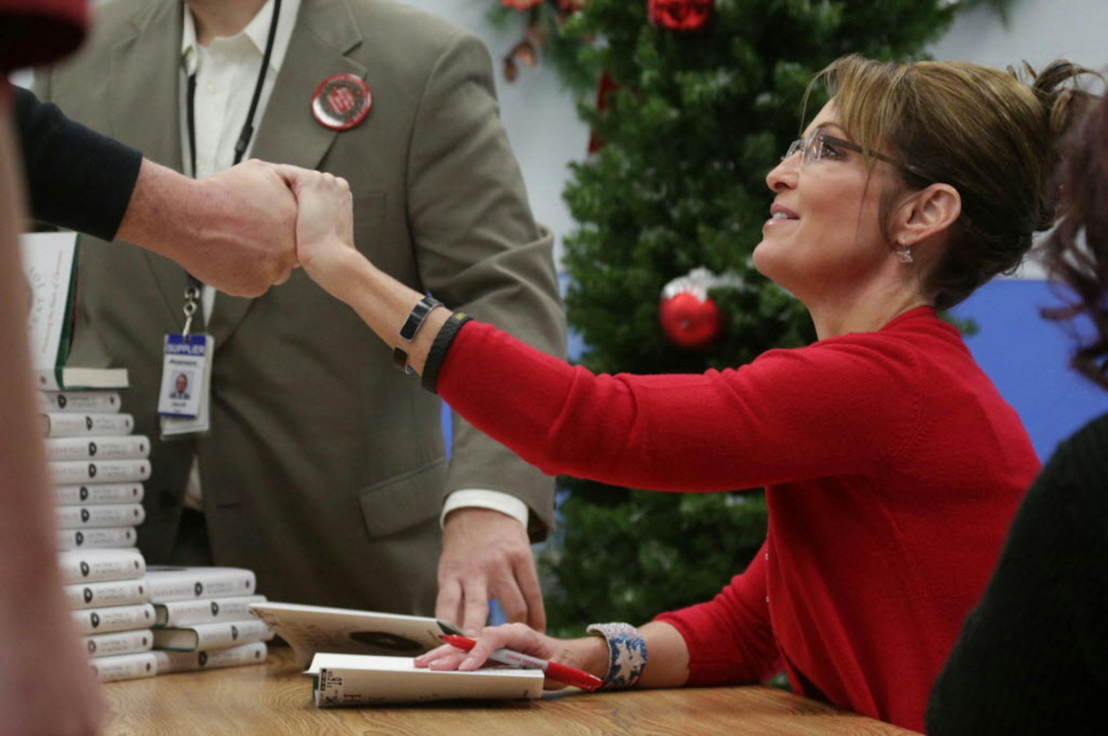 Sarah Palin shakes the hand of a woman as she signs copies of her book, "Good Tidings and Great Joy: Protecting the Heart of Christmas," at Walmart in Wausau, Wis., on Thursday, Nov. 14, 2013.