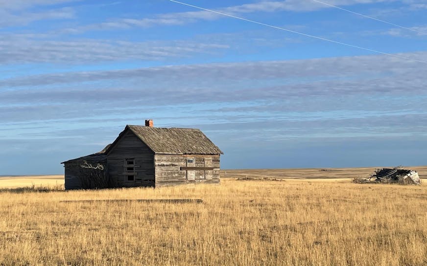 photo of a barn on the prairie under a blue sky