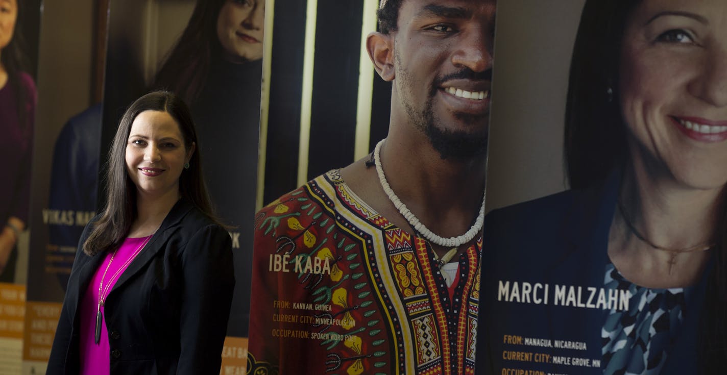 Tea Rozman Clark, executive director of Green Card Voices, stood among an exhibition at St. Paul College of stories that put a human face on immigration