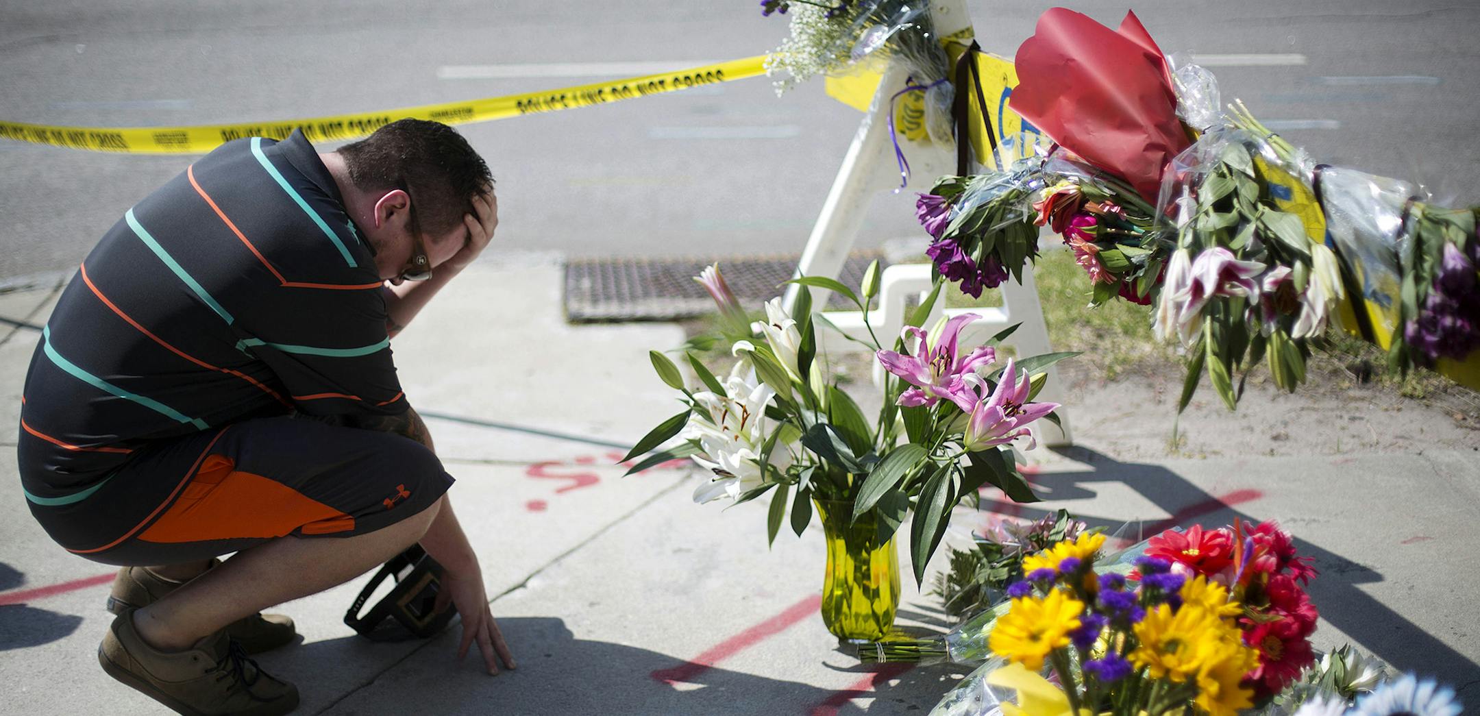 Noah Nicolaisen, of Charleston, S.C., kneels at a makeshift memorial, Thursday, June 18, 2015, down the street from where a man opened fire Wednesday night during a prayer meeting inside the Emanuel AME Church, killing several people in what authorities are calling a hate crime. (AP Photo/David Goldman) ORG XMIT: MIN2015061813574350