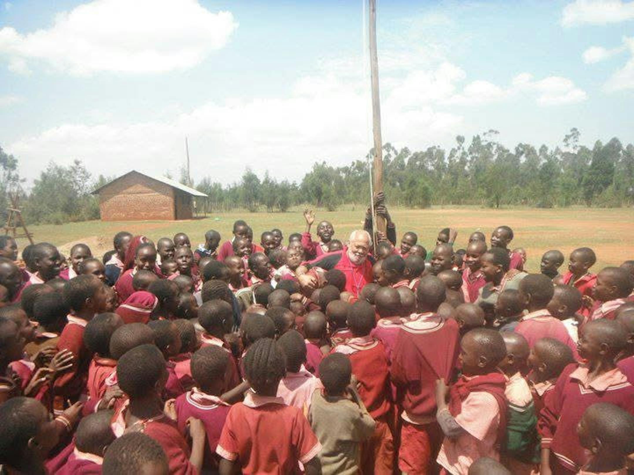 Wallace "Jack" Jackman takes a picture with children in Kenya after helping to get a firetruck into the country.