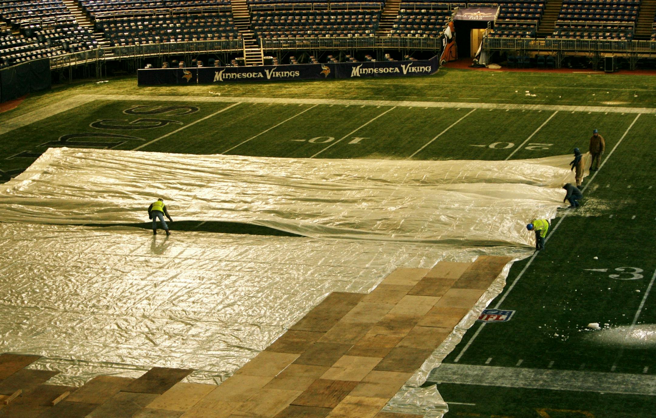 Workers lay plastic over a plywood base on the Metrodome floor.