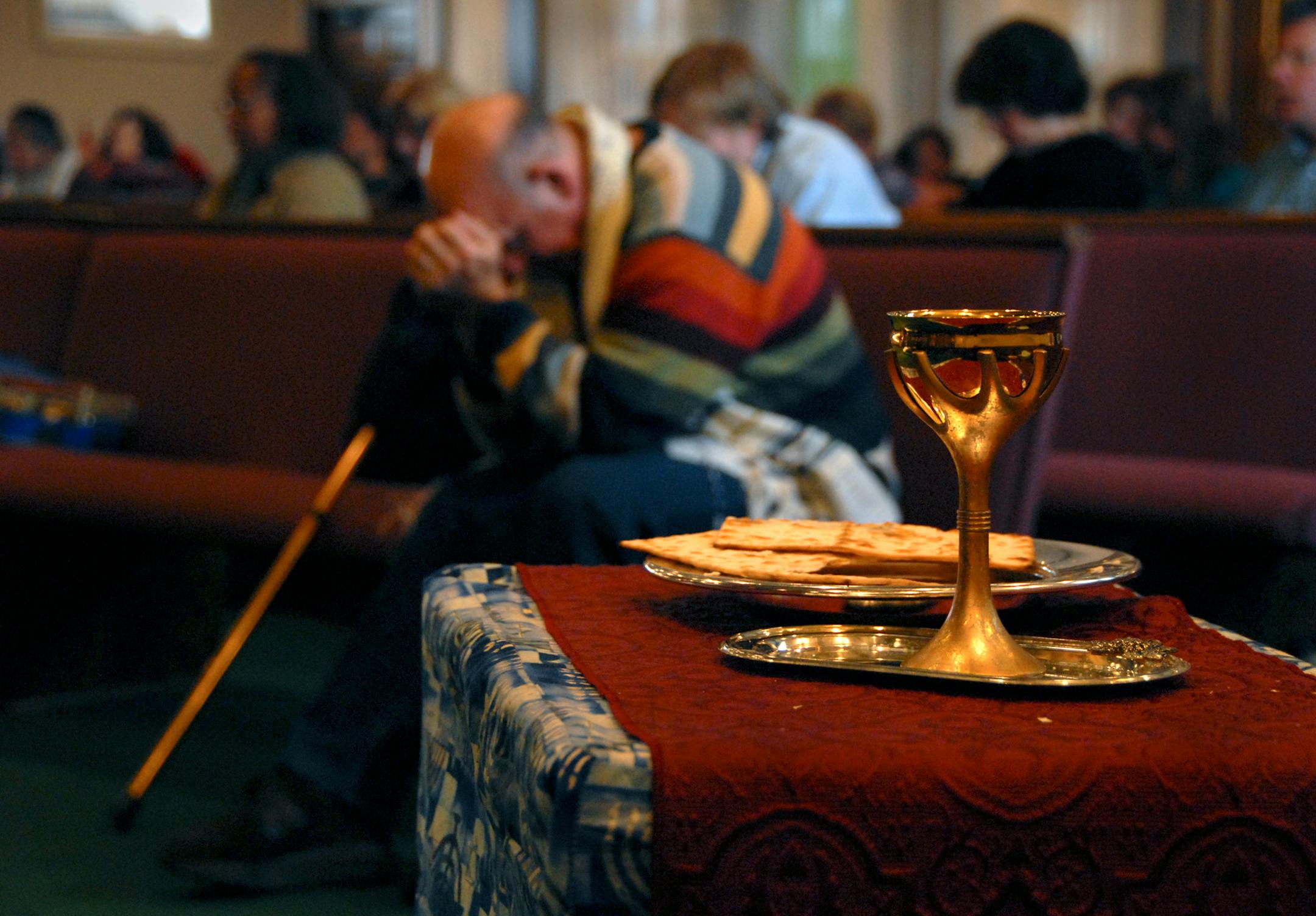 Bruce Neiger, associate Messianic Rabbi, bowed his head in prayer. In the foreground is the communion cup and Matzah. Members of the congregation can come up at any time during praise and worship and take communion.