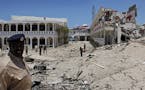 Somali soldiers stand near to a building destroyed by a blast near the presidential palace in the capital Mogadishu, Somalia Tuesday, Aug. 30, 2016. A